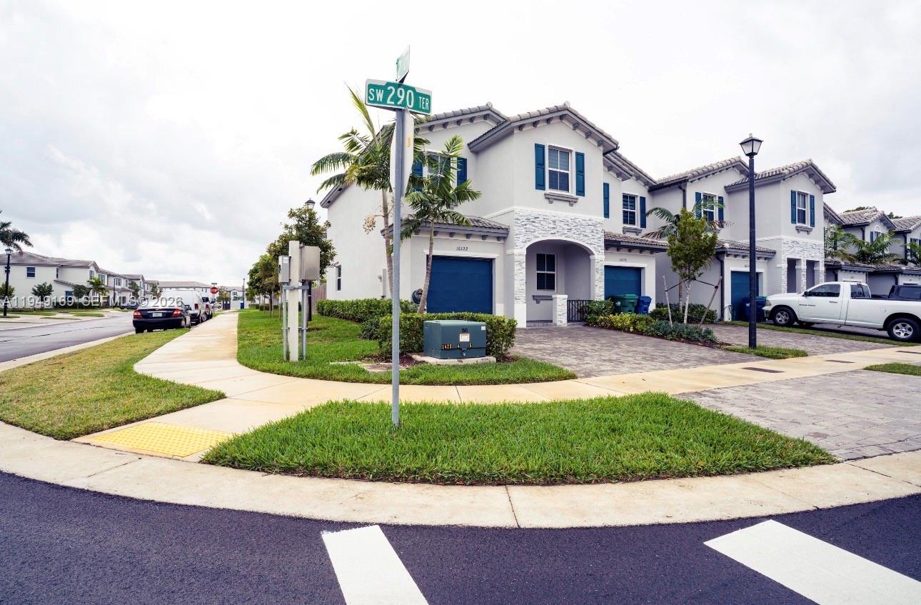 A two-story townhouse with a paved driveway, blue garage doors, and a street sign — 16222 SW 290th Ter, Homestead FL 33033, HOMESTEAD, FL