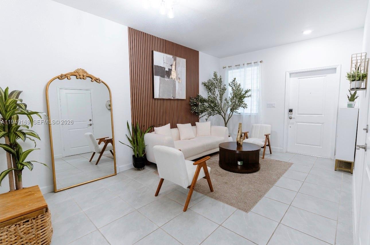 A living room features a slatted wood accent wall, white sofa, and a large gold mirror — 16222 SW 290th Ter, Homestead FL 33033, HOMESTEAD, FL