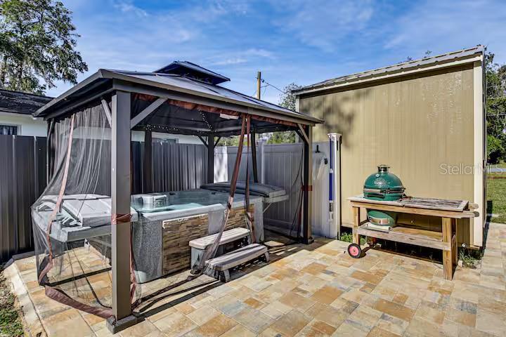 A backyard patio features a hot tub under a gazebo and a green grill on a table — 5185 S ALLIGATOR PLACE, FLORAL CITY, FL