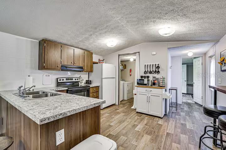 A kitchen features wood cabinets, granite-look countertops, stainless steel appliances, and wood-look flooring — 5185 S ALLIGATOR PLACE, FLORAL CITY, FL