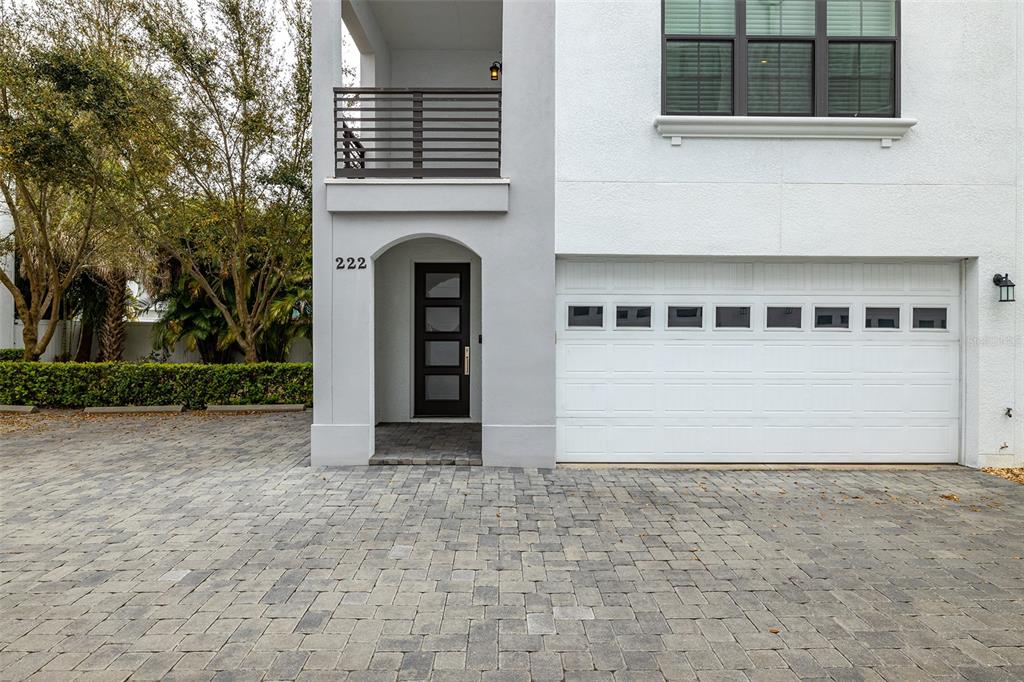 A two-story house exterior features a white facade, a gray entryway, and a paved driveway — 222 S AUDUBON AVENUE, TAMPA, FL