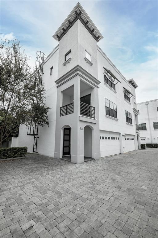 A three-story white townhouse with a corner balcony, a metal fire escape, and a paved driveway — 222 S AUDUBON AVENUE, TAMPA, FL