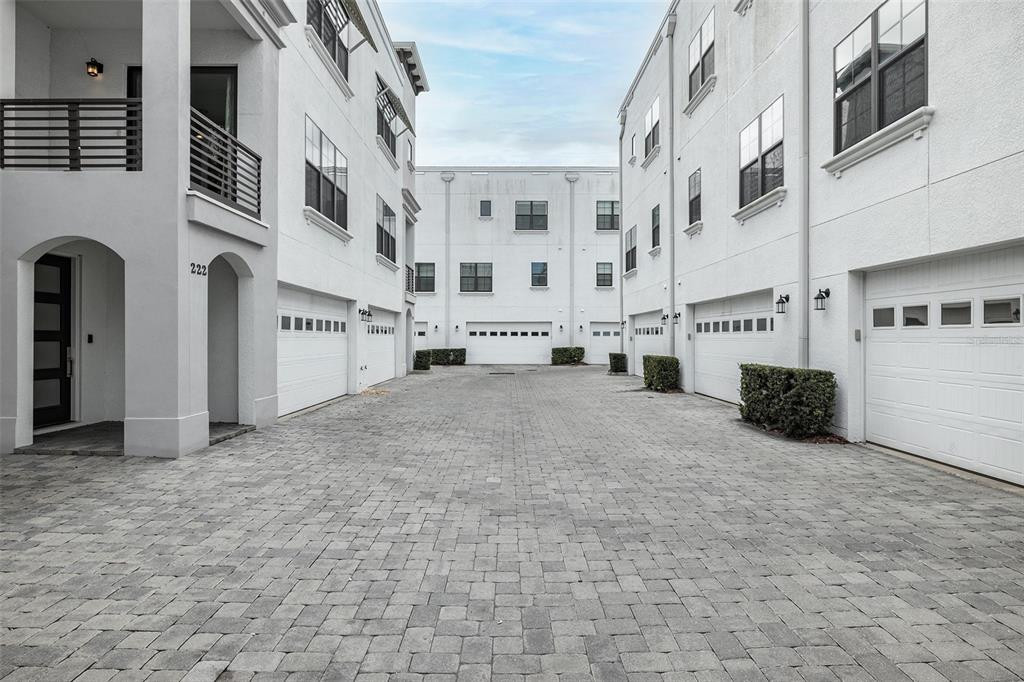 A paved alleyway sits between two white multi-story townhouses with garage doors and balconies — 222 S AUDUBON AVENUE, TAMPA, FL