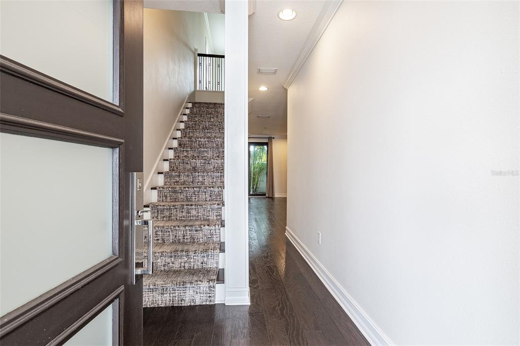 A foyer features a staircase with patterned carpet, dark hardwood floors, and a glass-paneled door — 222 S AUDUBON AVENUE, TAMPA, FL