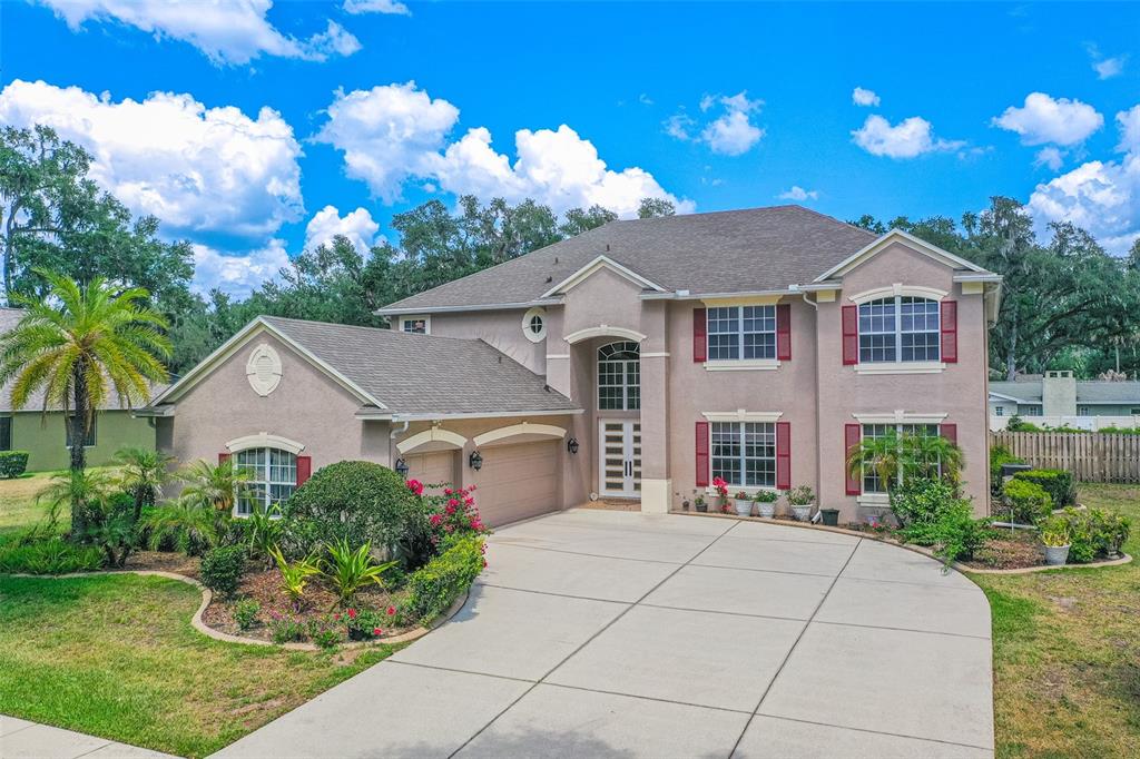 A two-story suburban house with a beige stucco exterior, red shutters, and a concrete driveway — 915 HICKORY FORK DRIVE, SEFFNER, FL