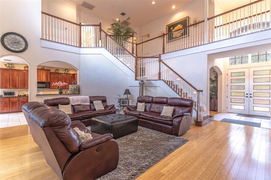 A spacious living room features a double staircase, leather furniture, and hardwood floors — 915 HICKORY FORK DRIVE, SEFFNER, FL
