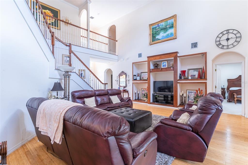 A living room with leather furniture, a built-in media center, and a staircase — 915 HICKORY FORK DRIVE, SEFFNER, FL