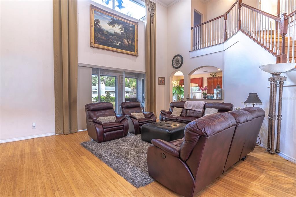 A high-ceilinged living room features leather furniture, a large painting, and a staircase — 915 HICKORY FORK DRIVE, SEFFNER, FL