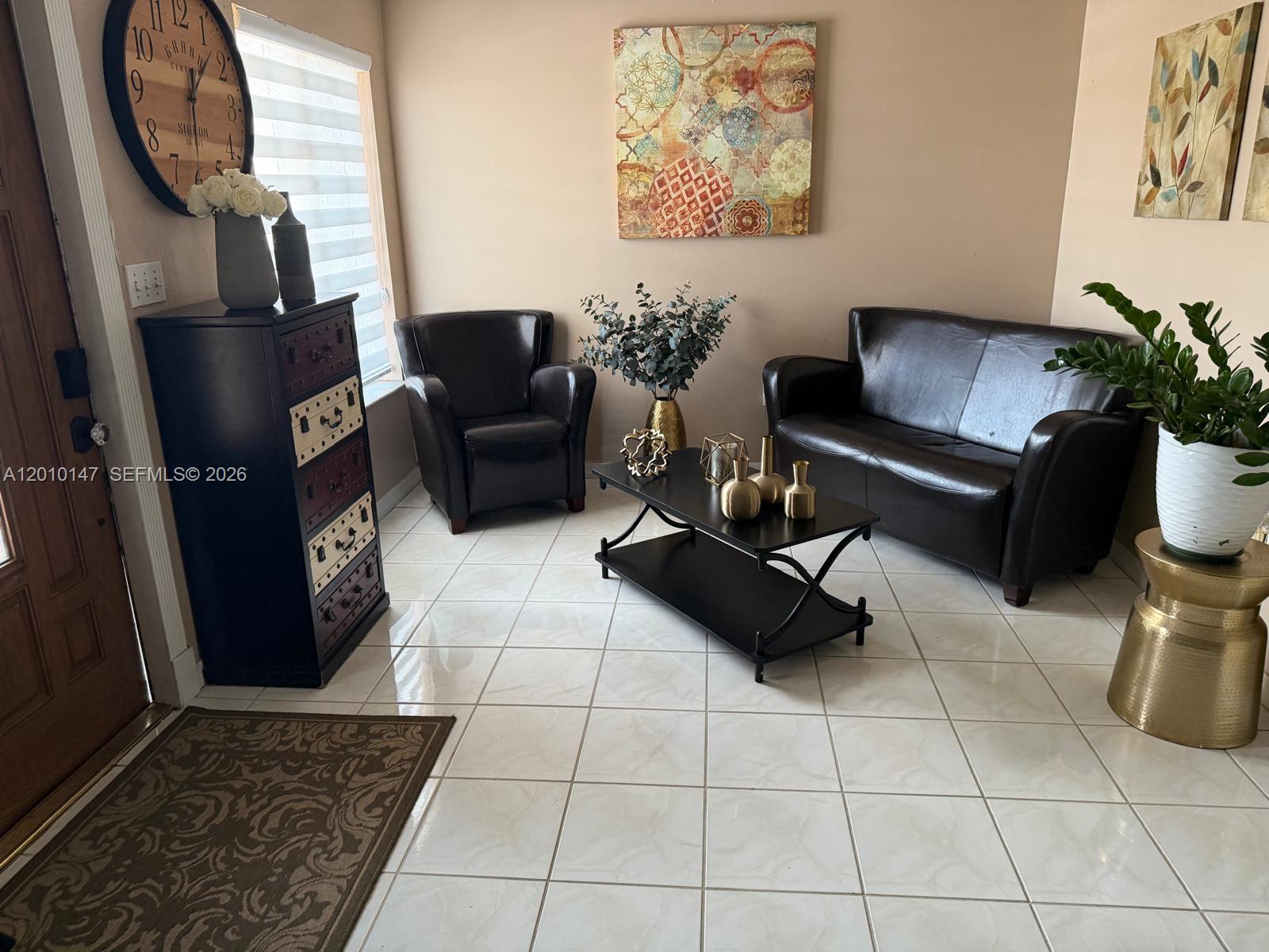 A living room features dark leather furniture, a black coffee table, and tiled flooring — 18109 SW 142nd Ct, Miami FL 33177, MIAMI, FL