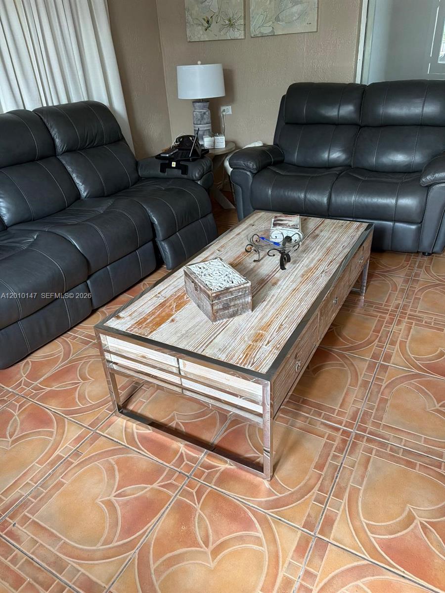 A living room features two dark leather sofas, a rustic coffee table, and tiled floors — 18109 SW 142nd Ct, Miami FL 33177, MIAMI, FL