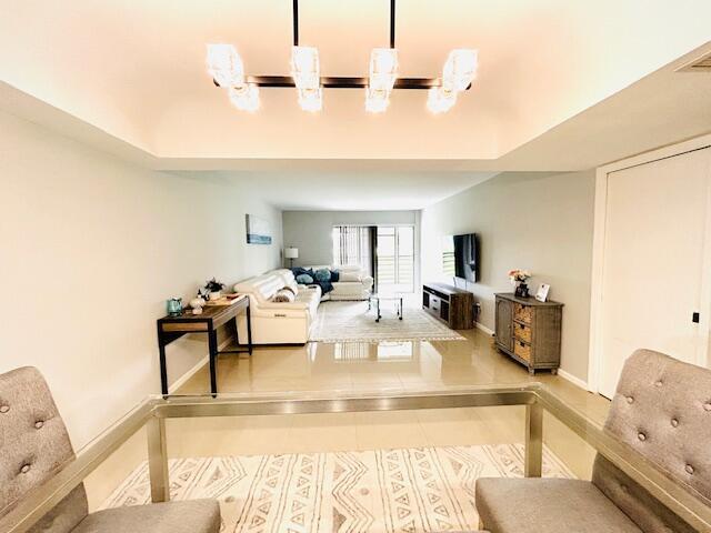 A living room features a white sofa, a television, and a modern chandelier — 23370 Carolwood Lane, Boca Raton FL 33428, BOCA RATON, FL