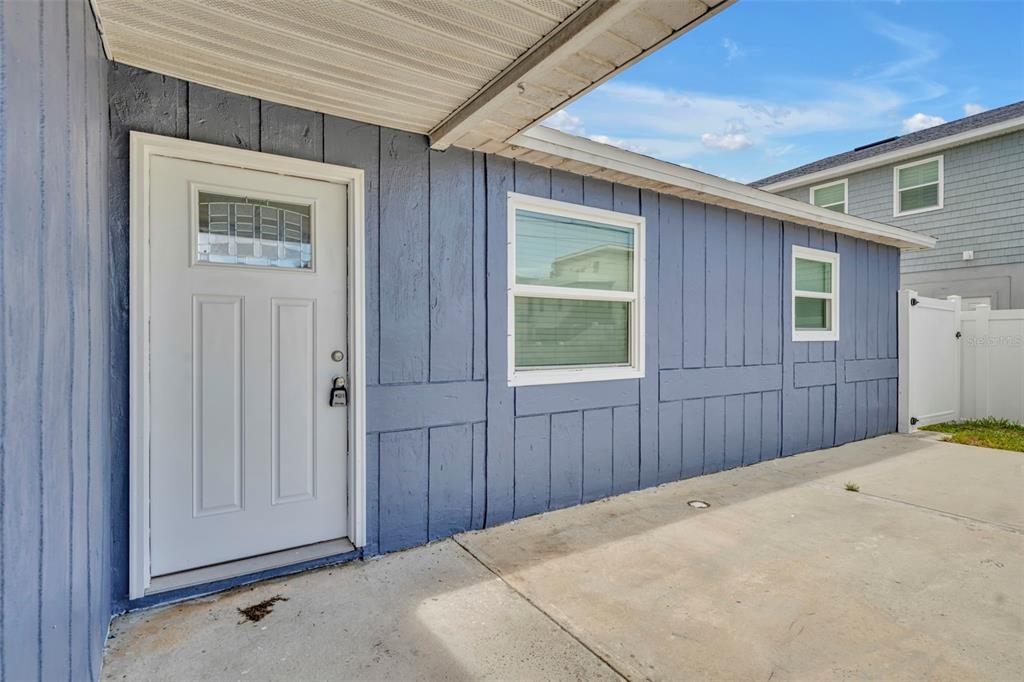 A blue exterior wall features a white front door and two windows above a concrete patio — 6416 BOATYARD DRIVE, HUDSON, FL