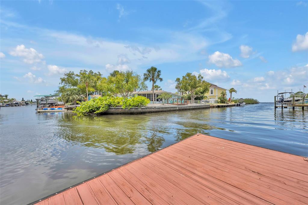 A wooden dock overlooks a canal with a waterfront house and lush trees — 6416 BOATYARD DRIVE, HUDSON, FL