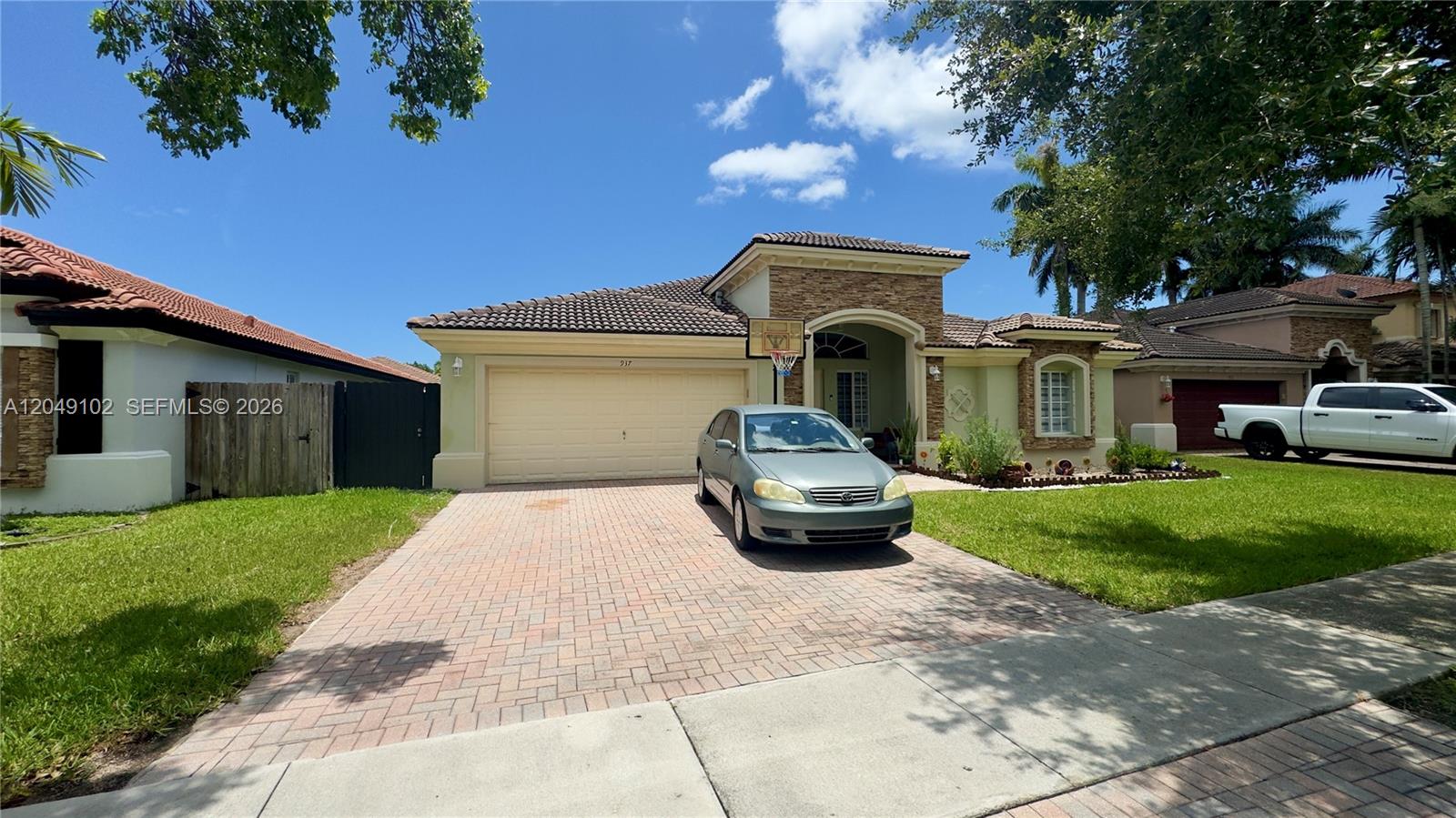 A single-story house with a beige stucco exterior, stone accents, and a paved driveway — 937 NE 35th Ave, Homestead FL 33033, HOMESTEAD, FL