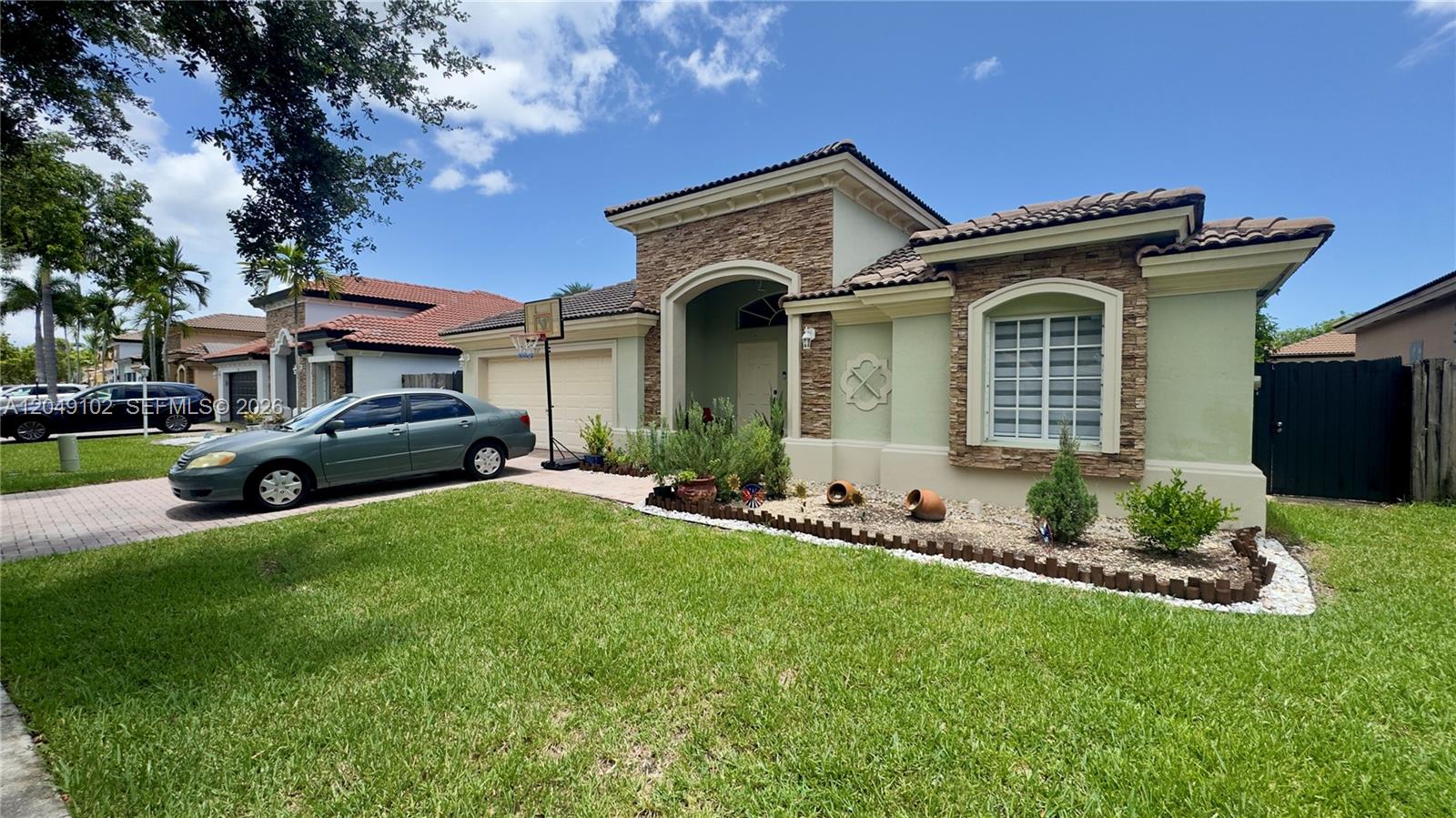 A single-story house with a stone facade, green stucco walls, and a paved driveway — 937 NE 35th Ave, Homestead FL 33033, HOMESTEAD, FL