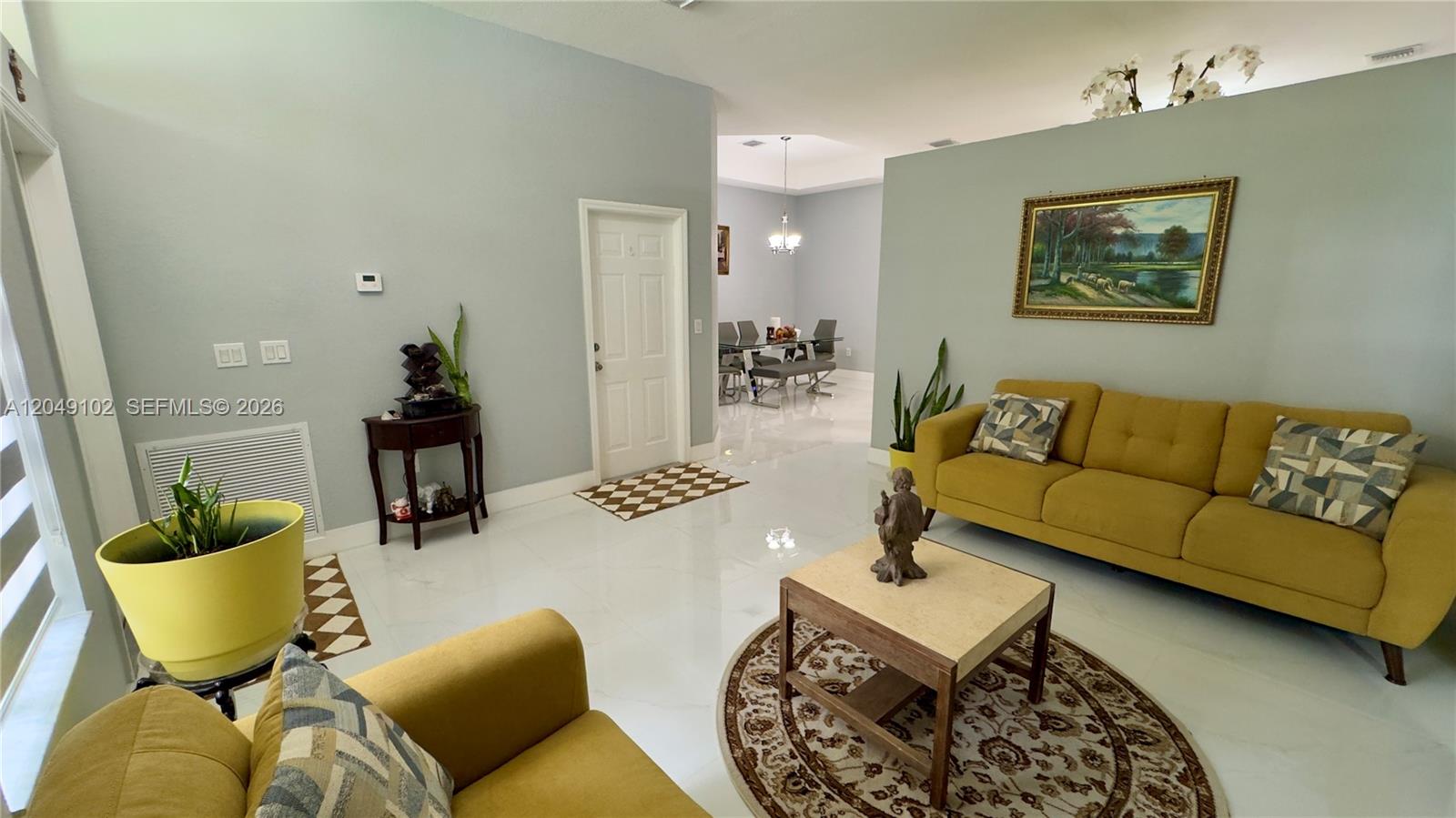 A living room features yellow sofas, a coffee table, and a dining area visible beyond — 937 NE 35th Ave, Homestead FL 33033, HOMESTEAD, FL
