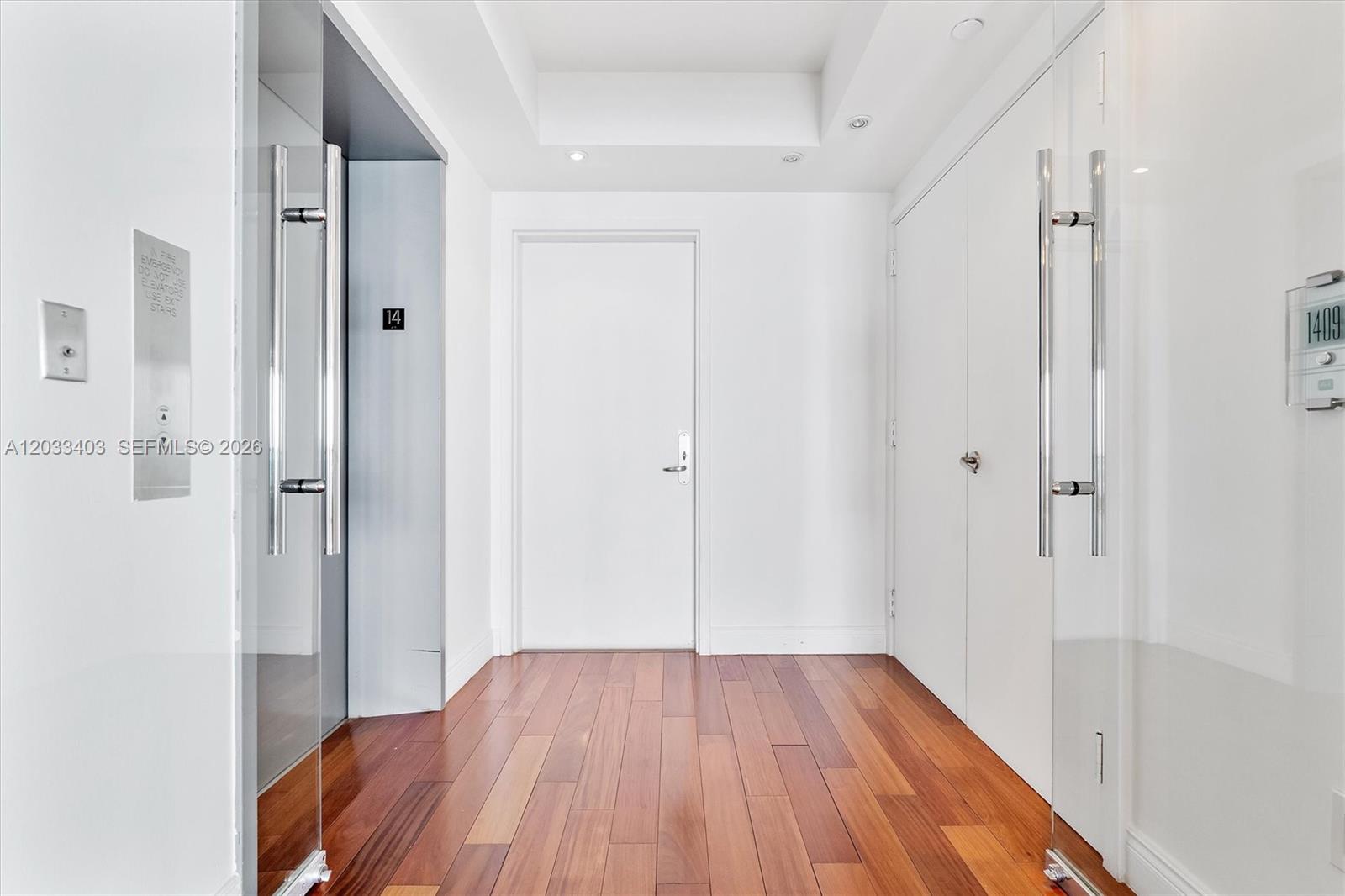 A hallway features hardwood floors, a central white door, and glass entry doors on both sides — 1331 Brickell Bay Dr # 1409, Miami FL 33131, MIAMI, FL