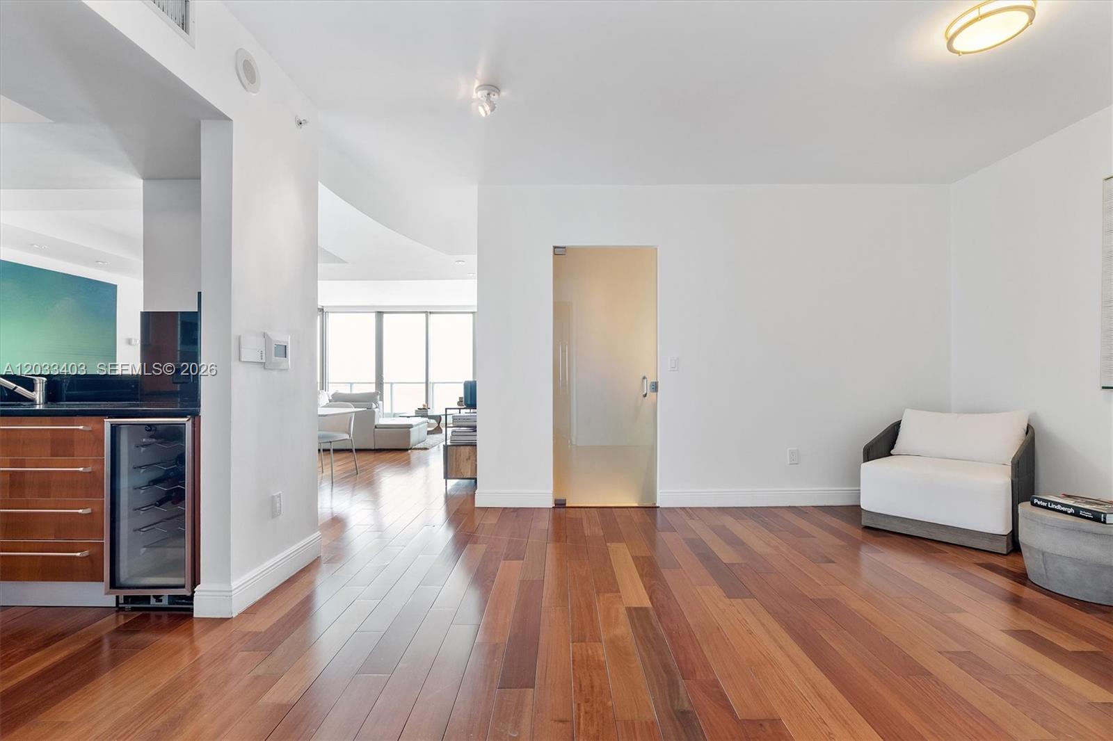 A room with hardwood floors, a frosted glass door, and a small white armchair — 1331 Brickell Bay Dr # 1409, Miami FL 33131, MIAMI, FL