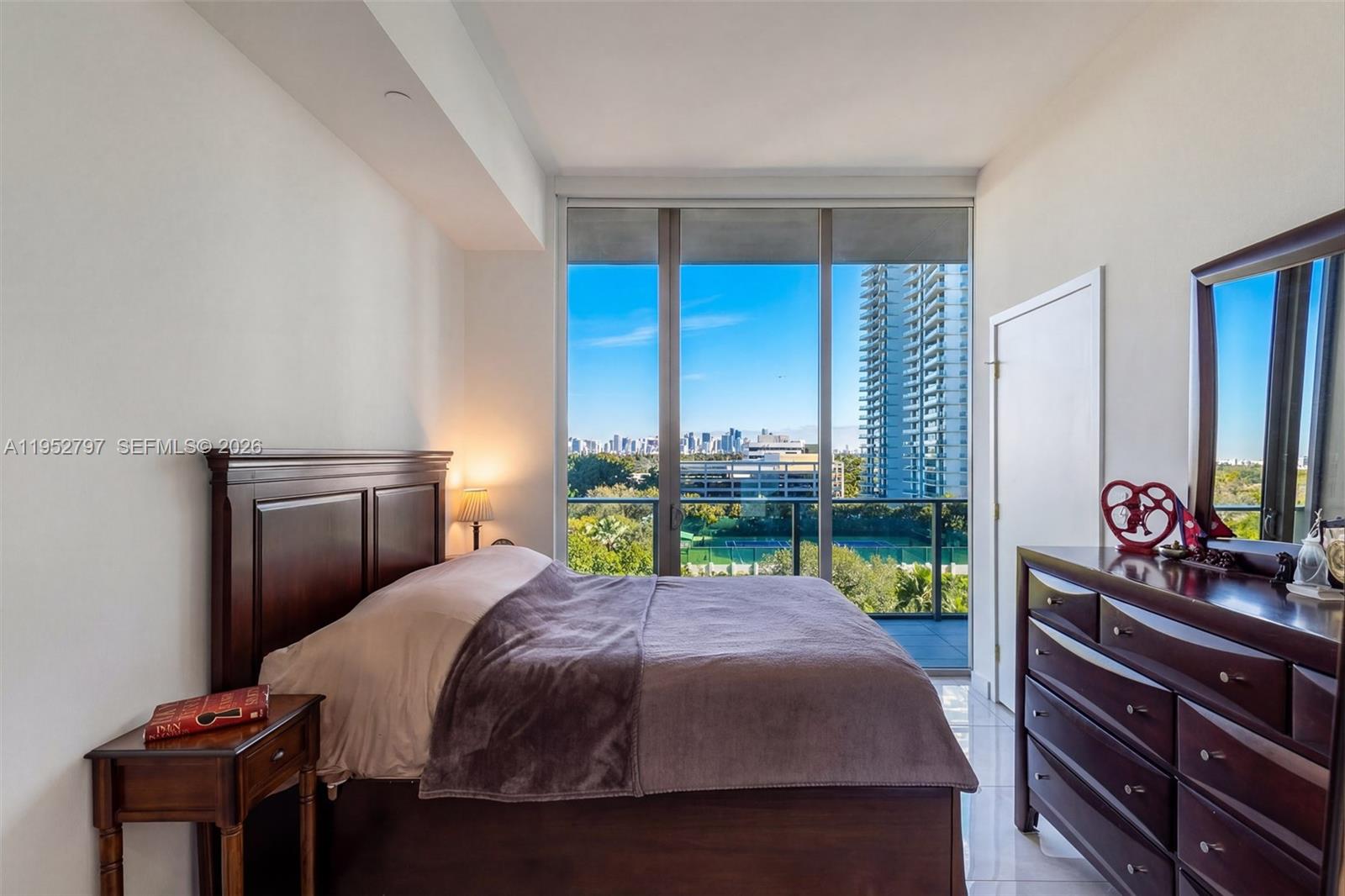 A bedroom features a dark wood bed, a matching dresser, and floor-to-ceiling windows with city views — 2678 Tigertail Ave # 612, Miami FL 33133, MIAMI, FL