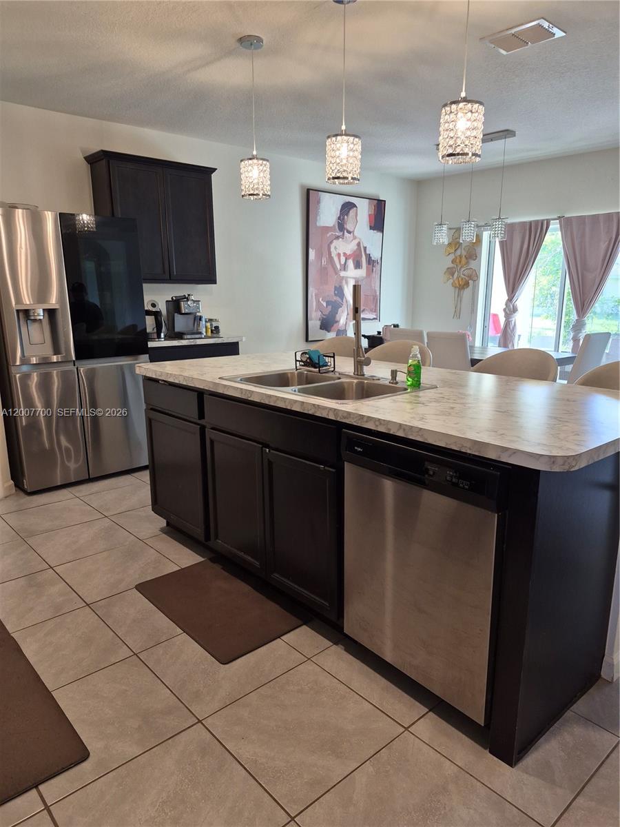 A kitchen island with a sink and dishwasher sits in front of dark cabinetry — 798 NW Bayshore Blvd, Port St. Lucie FL 34983, PORT ST. LUCIE, FL