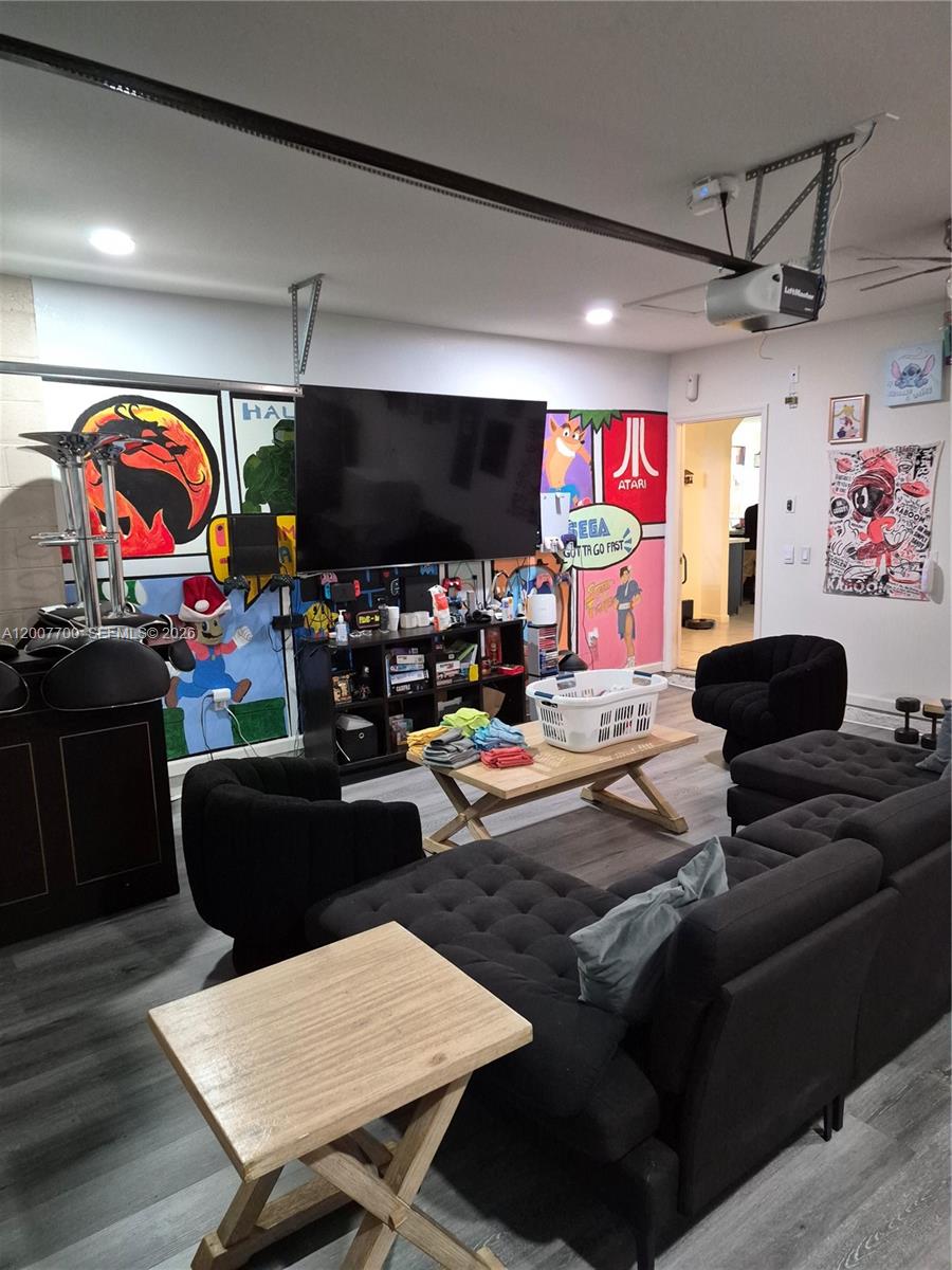 A garage converted into a game room with a large television, mural walls, and seating — 798 NW Bayshore Blvd, Port St. Lucie FL 34983, PORT ST. LUCIE, FL