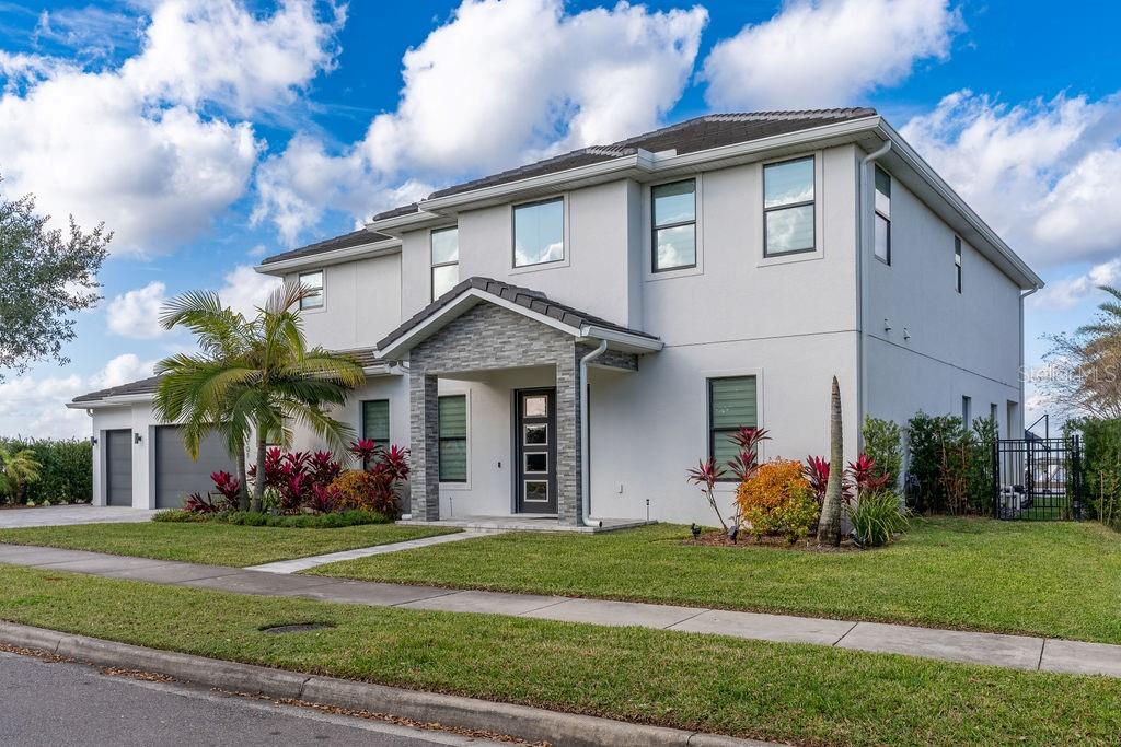 A two-story house with a gray stucco exterior, stone-accented entryway, and a palm tree — 7701 SUMMERLAKE POINTE BOULEVARD, WINTER GARDEN, FL