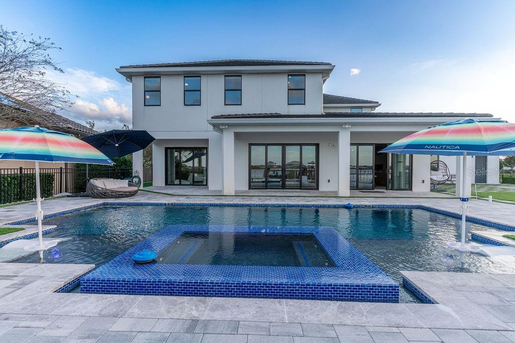 A two-story house exterior features a swimming pool with a tiled spa and patio — 7701 SUMMERLAKE POINTE BOULEVARD, WINTER GARDEN, FL