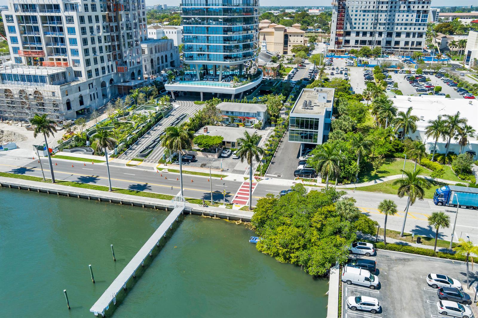 An aerial view shows a waterfront area with a modern high-rise, parking lots, and trees — 1301 S Flagler Drive, West Palm Beach FL 33401, WEST PALM BEACH, FL