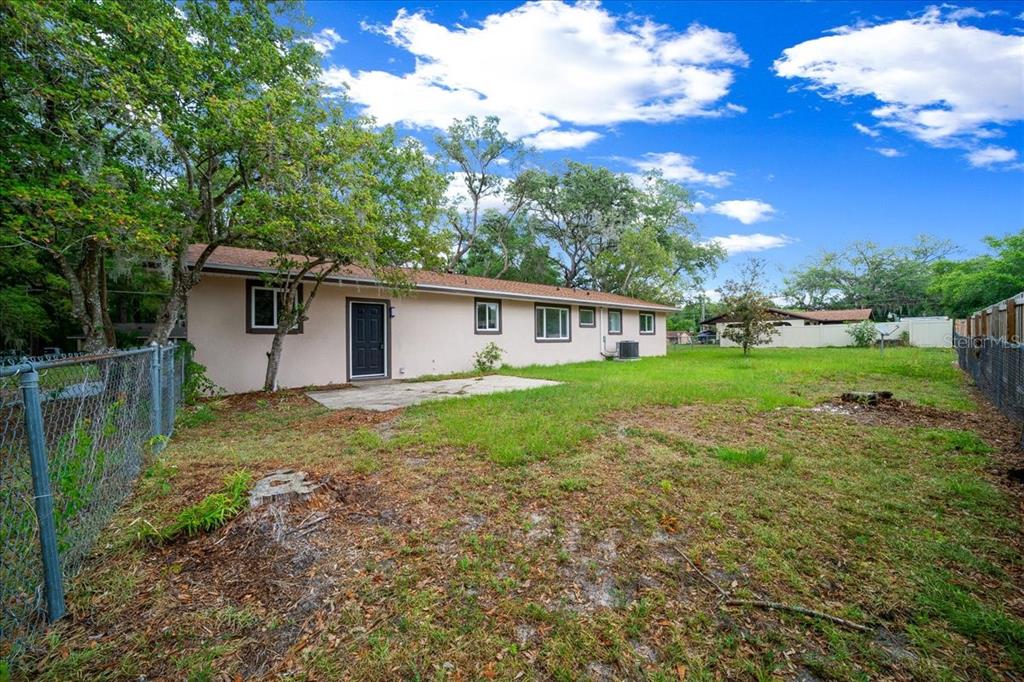 The exterior of a single-story house features a concrete patio and a large grassy yard — 4506 NE 10TH STREET, OCALA, FL
