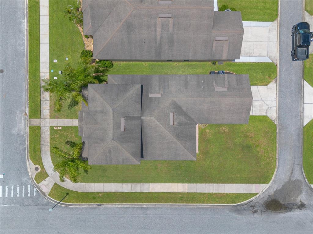 An aerial view shows two adjacent houses with dark shingled roofs and surrounding lawns — 3321 MARSILI AVENUE, NEW SMYRNA BEACH, FL
