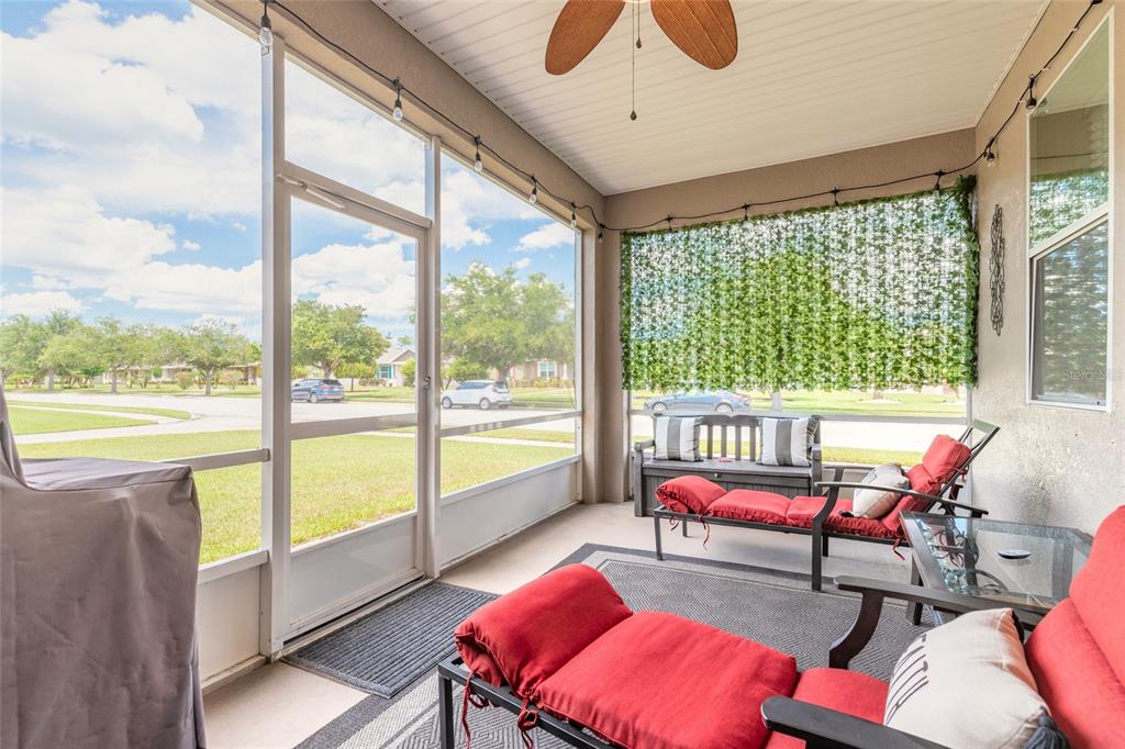 A screened-in patio features red lounge chairs, a bench, and a view of the neighborhood — 3321 MARSILI AVENUE, NEW SMYRNA BEACH, FL