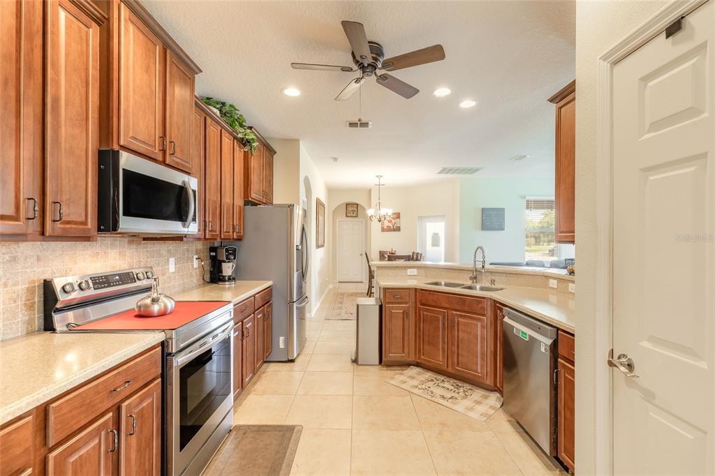 A kitchen features wood cabinets, stainless steel appliances, tile flooring, and a breakfast bar — 3321 MARSILI AVENUE, NEW SMYRNA BEACH, FL
