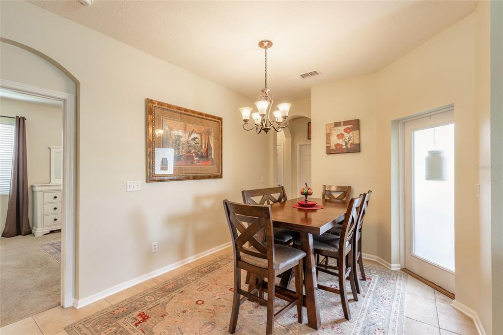 A dining room with a wooden table, four chairs, a chandelier, and a patterned area rug — 3321 MARSILI AVENUE, NEW SMYRNA BEACH, FL