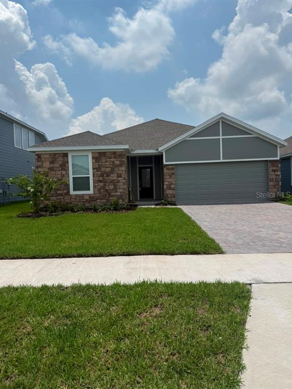 A single-story house features a stone facade, a gray garage, and a paved driveway — 5133 ARROWFEATHER COURT, ST CLOUD, FL