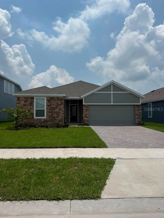 A single-story house with a stone facade, gray garage, and a paved driveway — 5133 ARROWFEATHER COURT, ST CLOUD, FL
