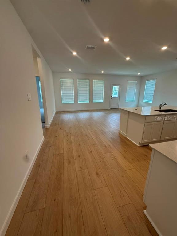 An open-concept kitchen and living area features light wood-look flooring and recessed lighting — 5133 ARROWFEATHER COURT, ST CLOUD, FL