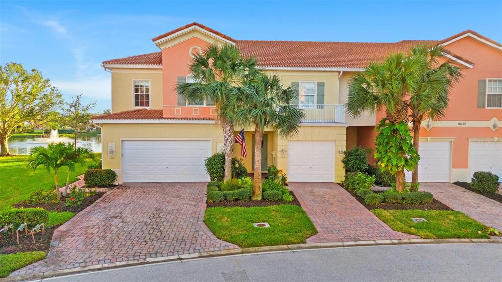 A two-story townhouse with a paved driveway, a single-car garage, and a balcony — 16150 VIA SOLERA CIRCLE UNIT 102, FORT MYERS, FL