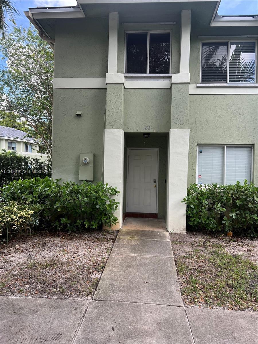 A two-story green stucco building features a white front door and a concrete walkway — 183 Hidden Ct Rd # 33, Hollywood FL 33023, HOLLYWOOD, FL