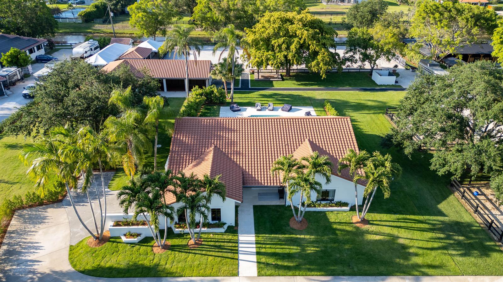 An aerial view of a single-story house with a tiled roof, pool, and palm trees — 14828 Rolling Rock Place, Wellington FL 33414, WELLINGTON, FL