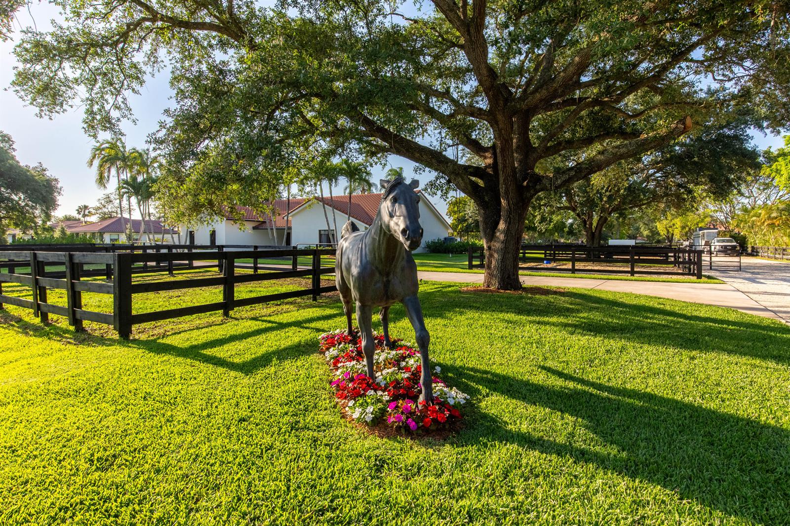 A bronze horse statue stands in a grassy yard before a house and large tree — 14828 Rolling Rock Place, Wellington FL 33414, WELLINGTON, FL