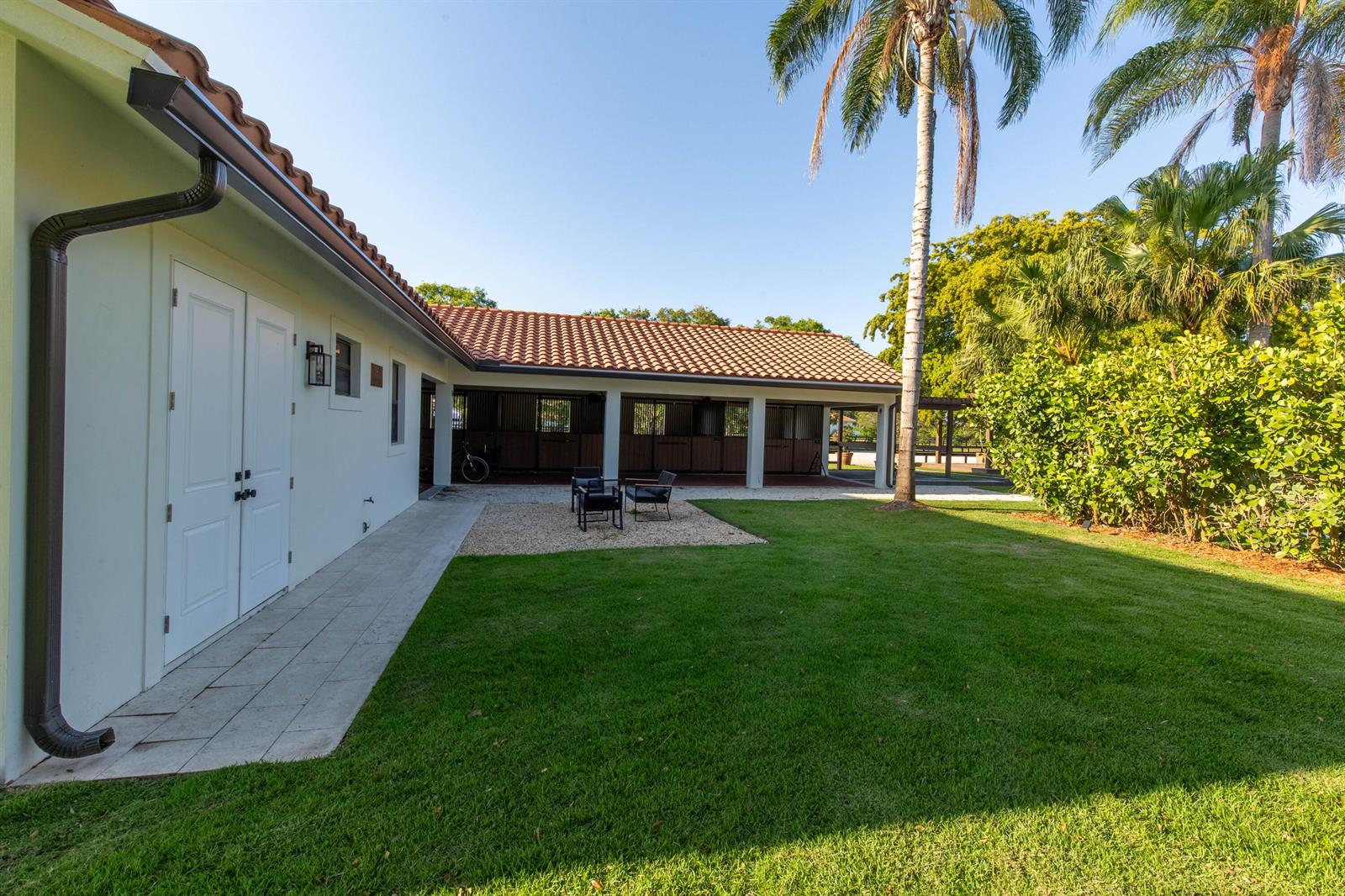 A view of a backyard with a lawn, a gravel patio, and a horse stable — 14828 Rolling Rock Place, Wellington FL 33414, WELLINGTON, FL