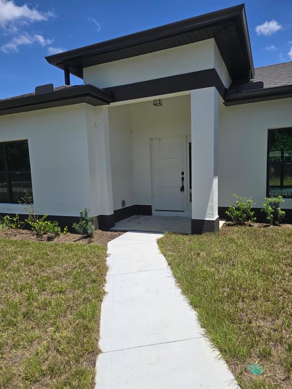 A modern single-story house with a white stucco exterior, dark trim, and a concrete walkway — 4240 LAS ALMANOS AVENUE, NORTH PORT, FL