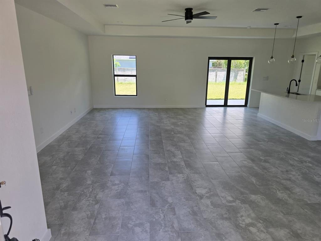 An open-concept living area features gray tile flooring, a ceiling fan, and sliding glass doors — 4240 LAS ALMANOS AVENUE, NORTH PORT, FL
