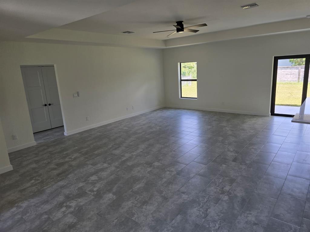 A spacious room with gray tile flooring, a tray ceiling, and a sliding glass door — 4240 LAS ALMANOS AVENUE, NORTH PORT, FL