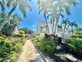 A brick walkway leads toward a two-story white building surrounded by palm trees and landscaping — 3021 Florida Boulevard, Delray Beach FL 33483, DELRAY BEACH, FL