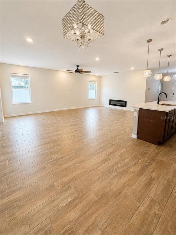 An open-concept living area features wood-look tile flooring, a kitchen island, and a fireplace — 433 SARDINIA CIRCLE, DAVENPORT, FL