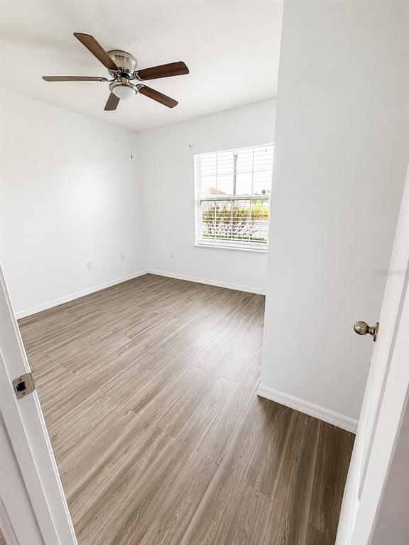 An empty bedroom features light wood-look flooring, white walls, a ceiling fan, and a window — 433 SARDINIA CIRCLE, DAVENPORT, FL