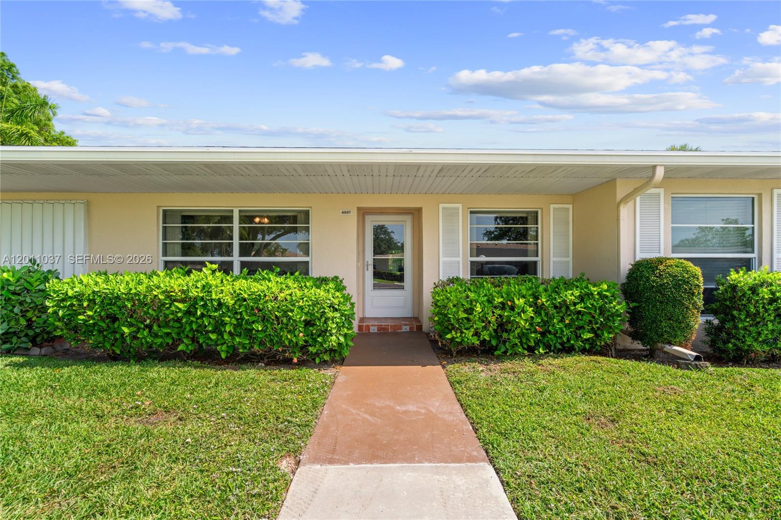 A single-story house exterior features a central front door, large windows, and manicured landscaping — 8887 Bella Vista Dr # 8887, Boca Raton FL 33433, BOCA RATON, FL