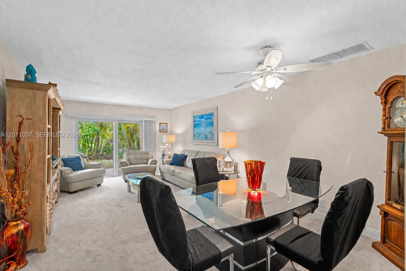 A living and dining room area features a glass table, neutral furniture, and a grandfather clock — 8887 Bella Vista Dr # 8887, Boca Raton FL 33433, BOCA RATON, FL