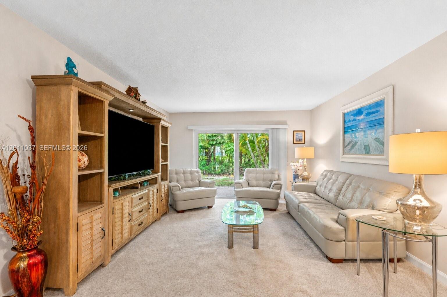 A living room features a large wooden entertainment center, beige leather seating, and sliding doors — 8887 Bella Vista Dr # 8887, Boca Raton FL 33433, BOCA RATON, FL